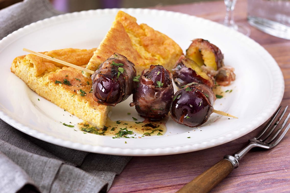 Tiroler Speckzwetschkenspieße mit Polentaschnitten, Gabel, Weinglas, Serviette, Teller